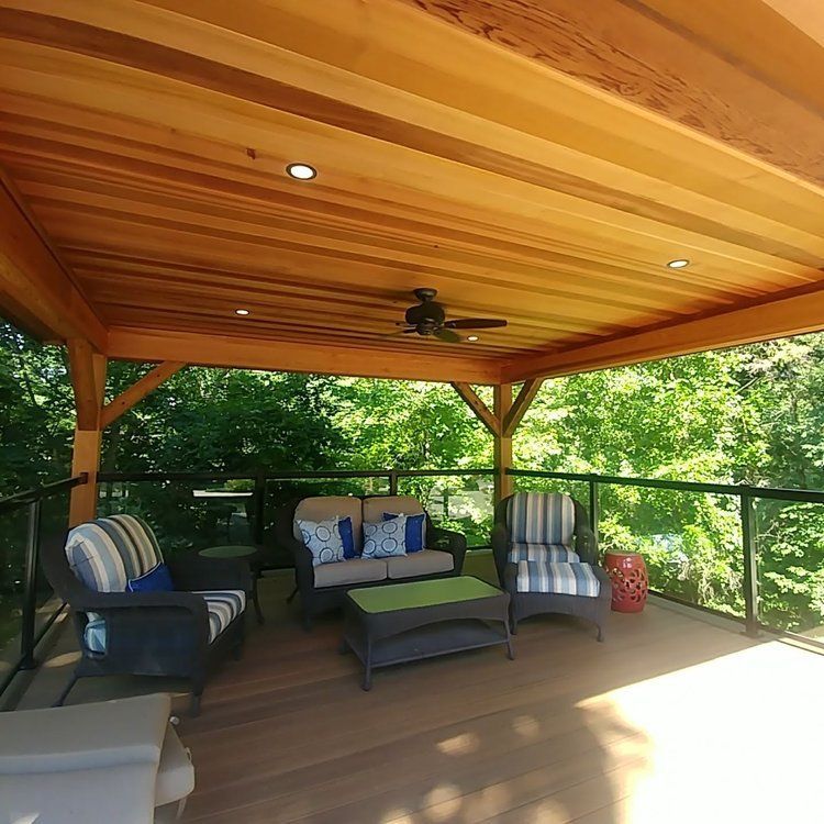 A wooden deck with furniture and a ceiling fan.