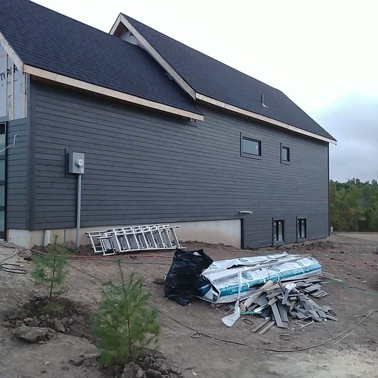 A large gray house with a ladder in front of it