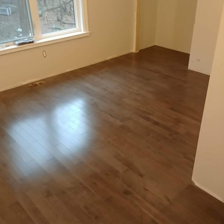 An empty room with a wooden floor and a window.