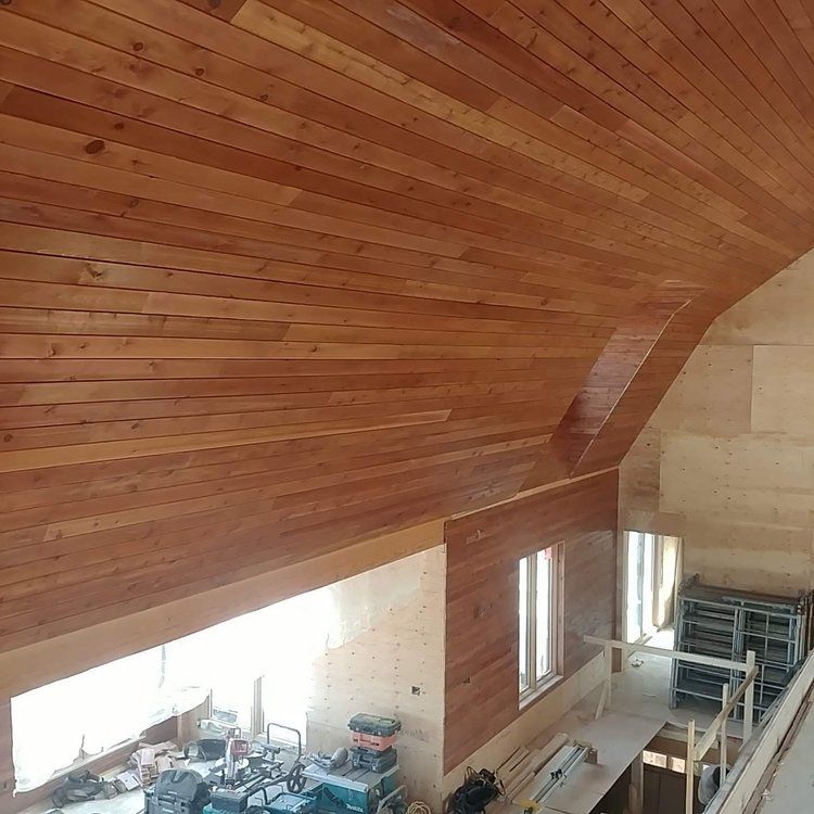 A room with a wooden ceiling and a lot of windows