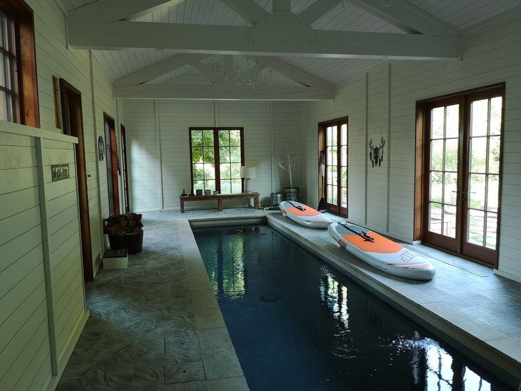 A large indoor swimming pool with kayaks in it