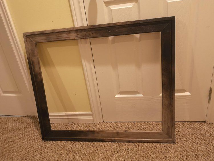 A picture frame is sitting on the floor in front of a door.