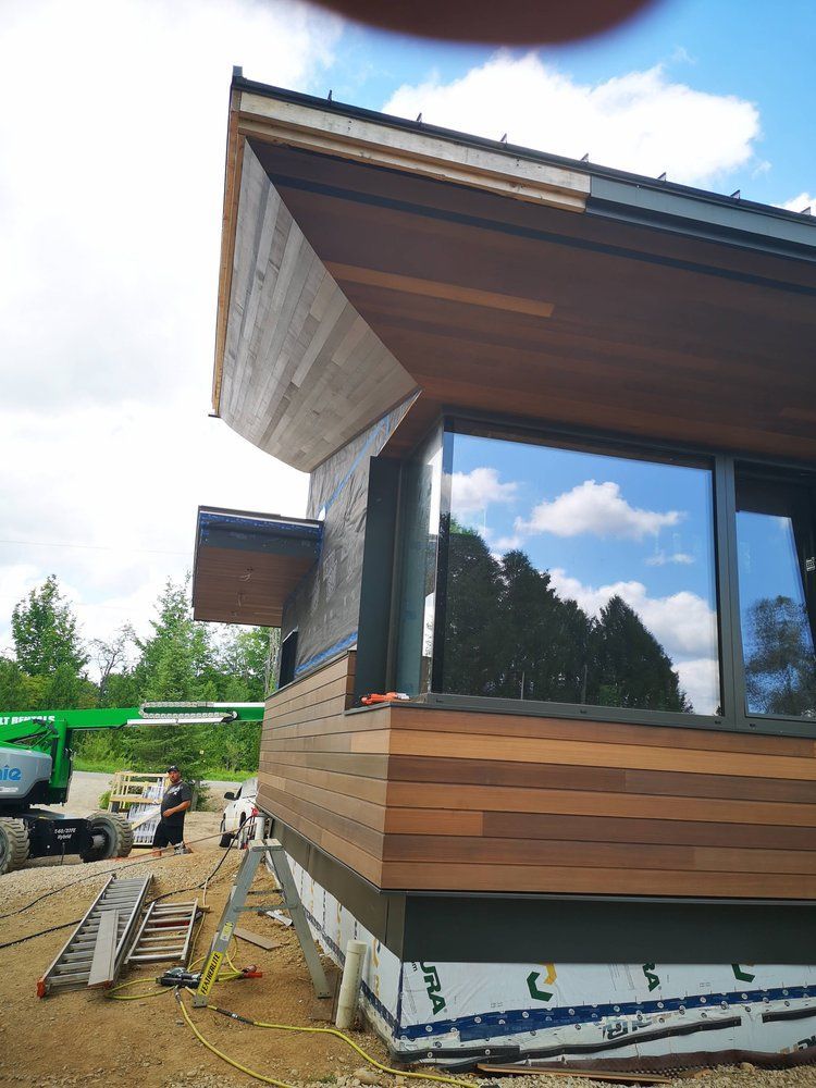A house is being built with wooden siding and a large window.