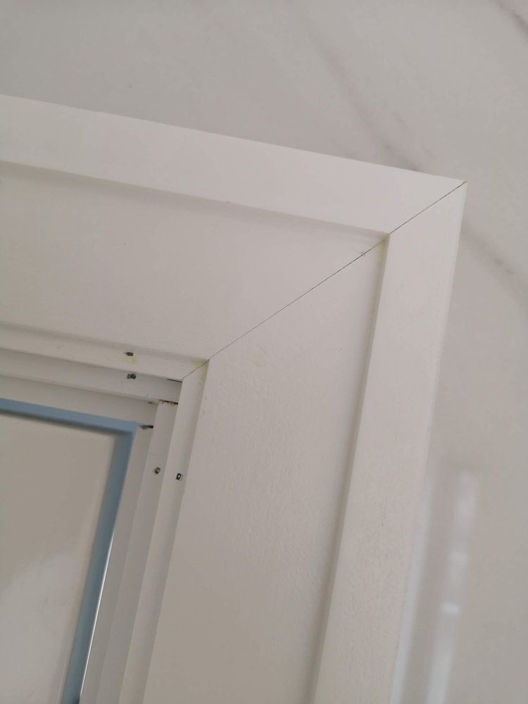 A close up of a white window frame on a white wall.