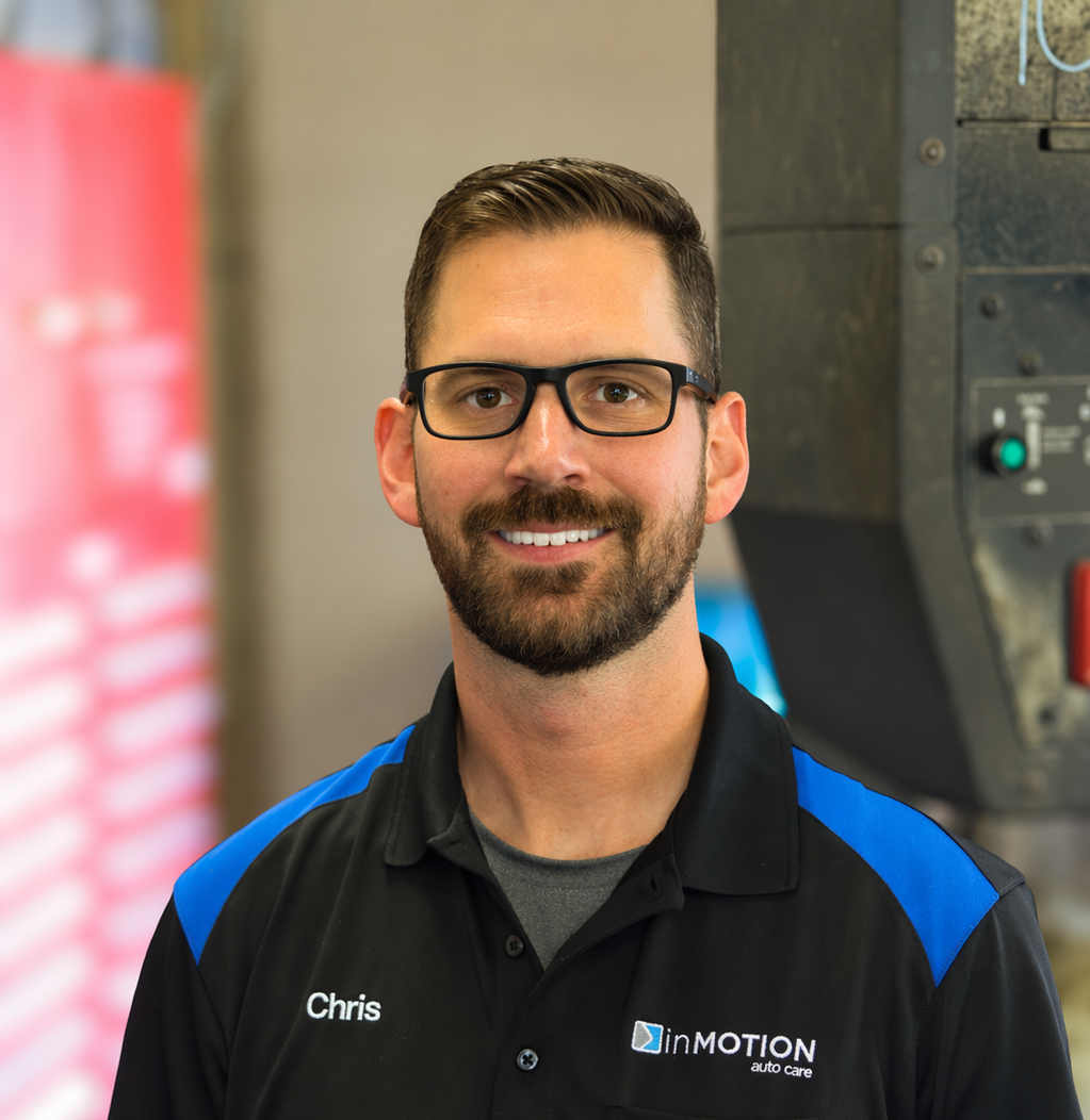Smiling man with glasses in a black and blue uniform shirt standing indoors