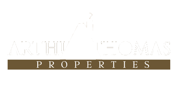 A logo for archi thomas properties with a building in the background.