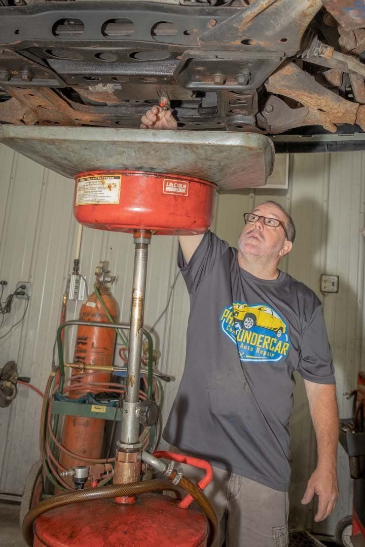 Our Mechanic is Draining Engine Oil in Clinton, MI - Phil's Complete Auto Repair