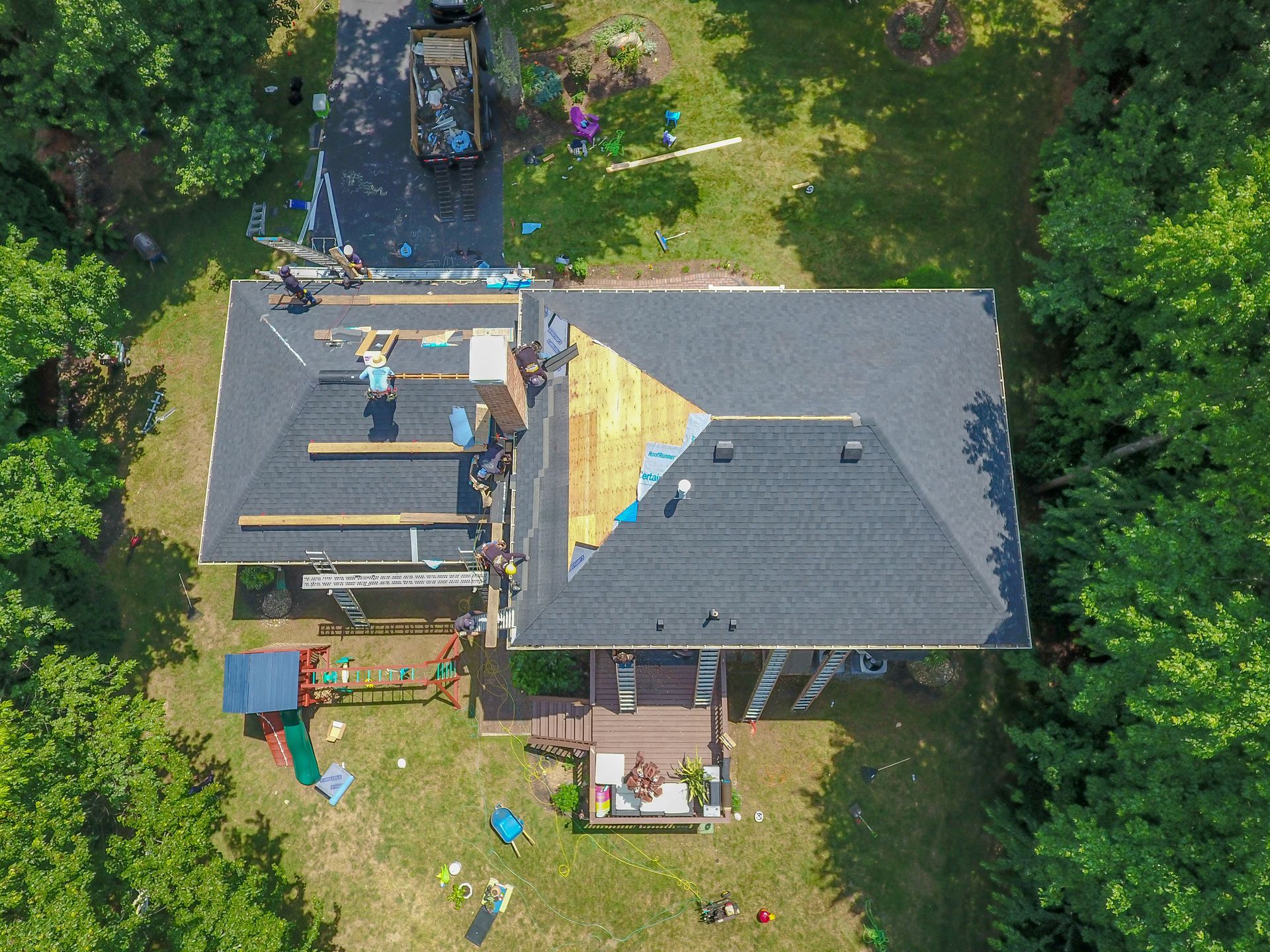 Aerial view of a roofing crew working on the roofing of a home, under the sun