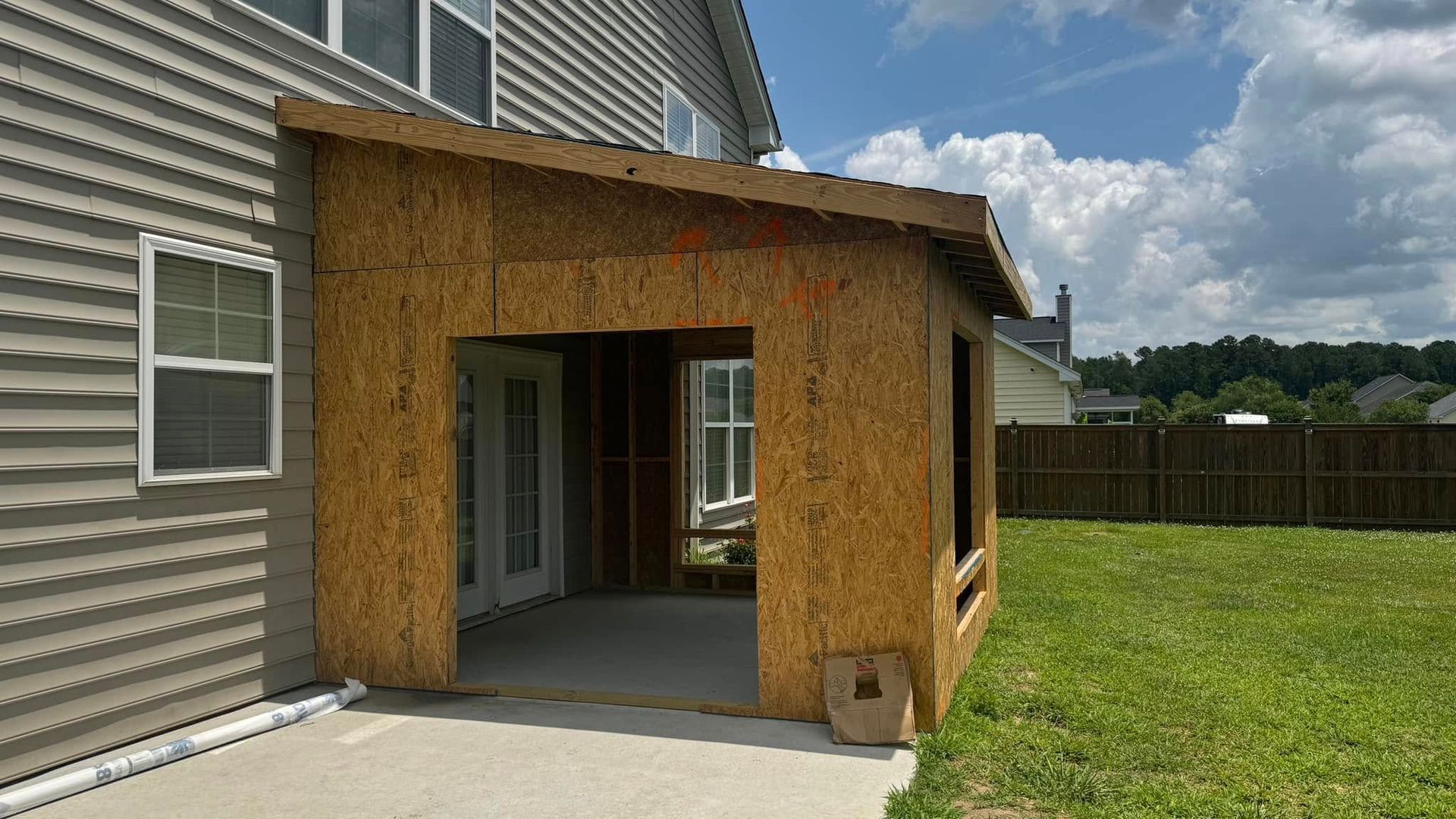 A house with a porch being built on the side of it.