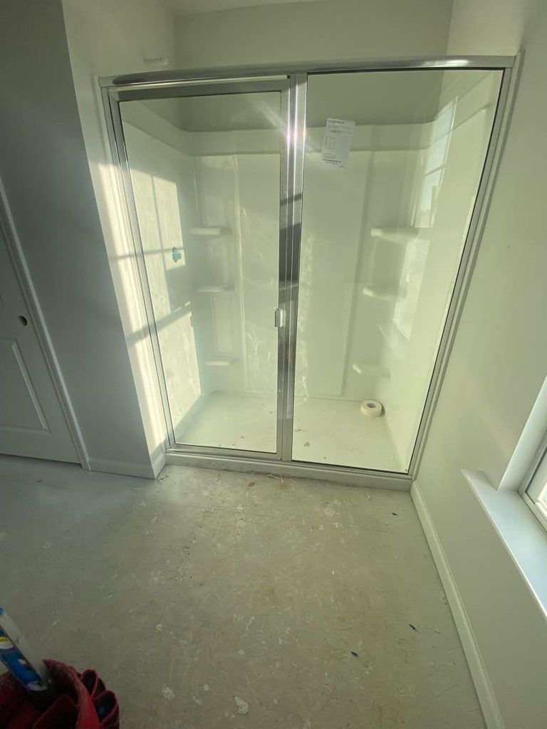 A bathroom with a sliding glass shower door and a window.