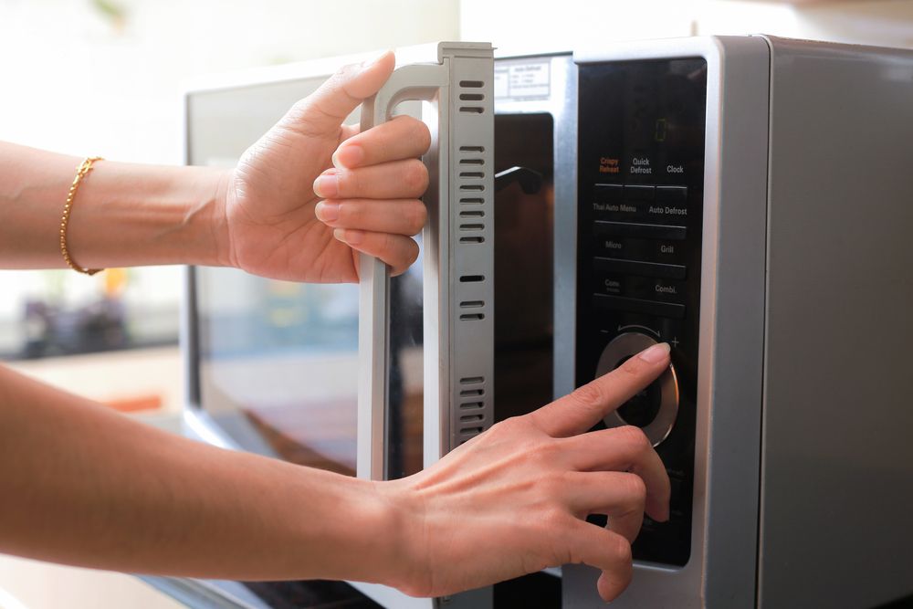 Woman Setting the Timer in the Microwave — Gold Coast Linen Hire in Tugun, QLD