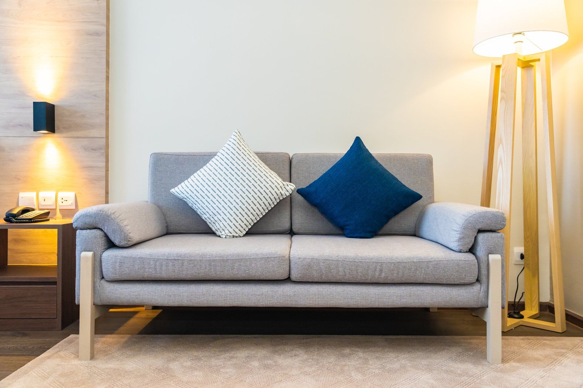 A couch with two pillows on it in a living room next to a lamp.