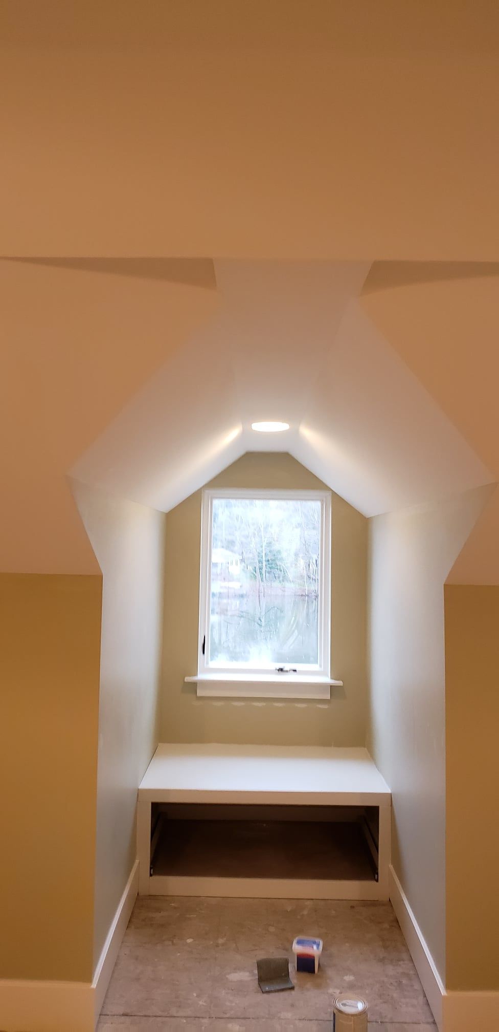 An interior shot of a room with a window seat. The room is freshly painted with a light beige color. The window is centered, with a seat below.
