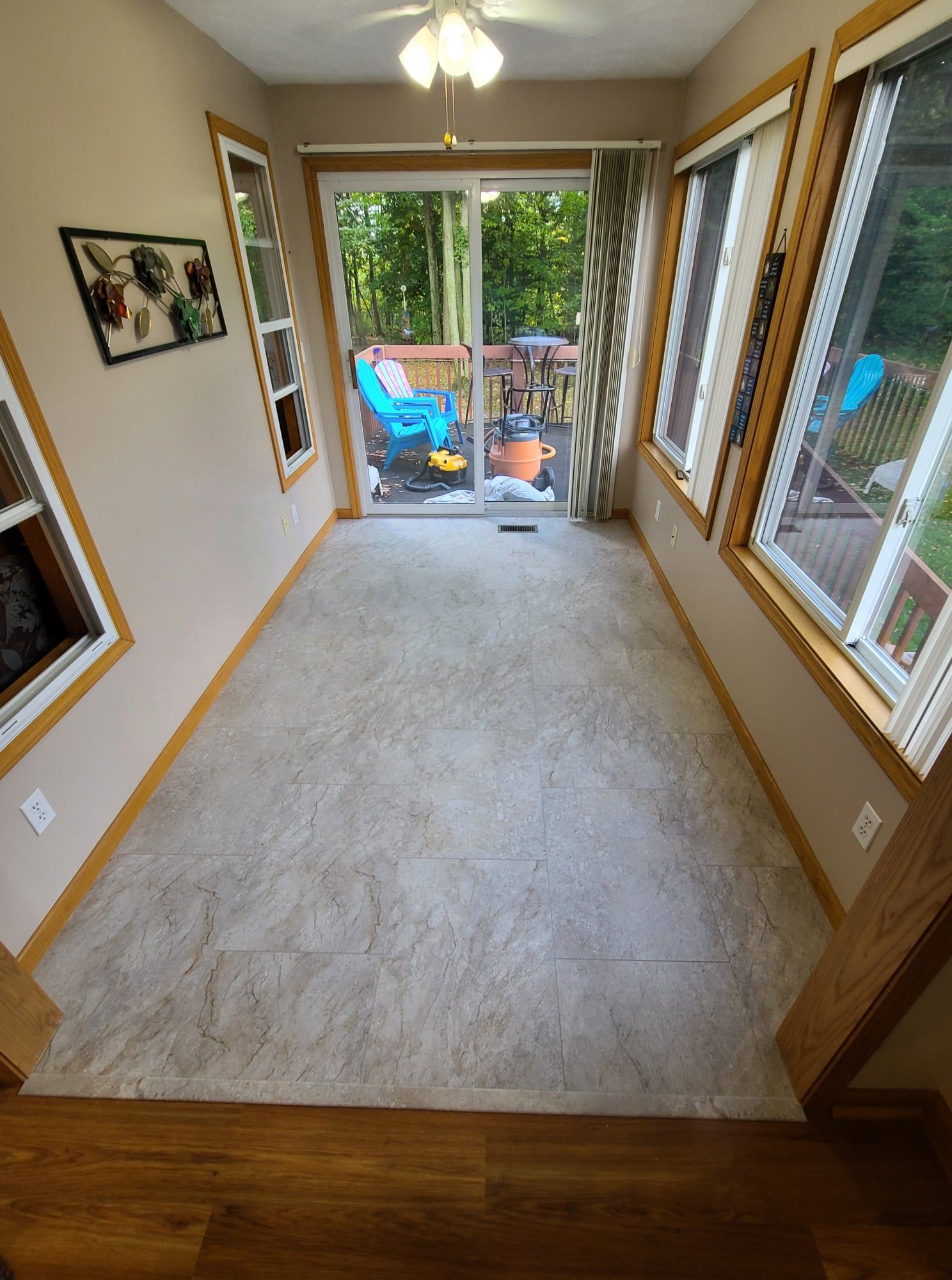 Narrow room with light-colored carpet, windows on two sides, and a sliding glass door to a deck.