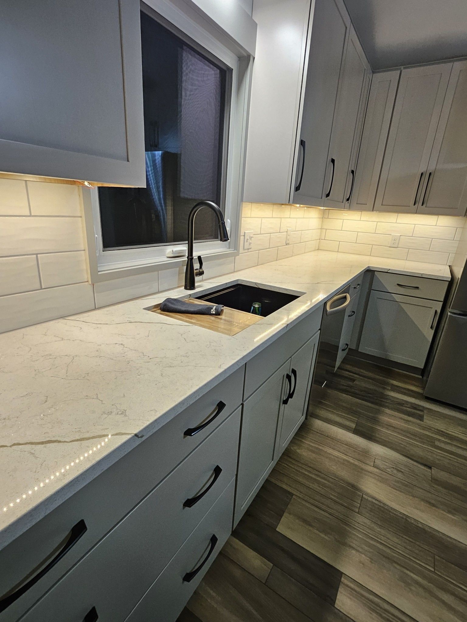 White kitchen with quartz countertops, black sink, and black hardware.