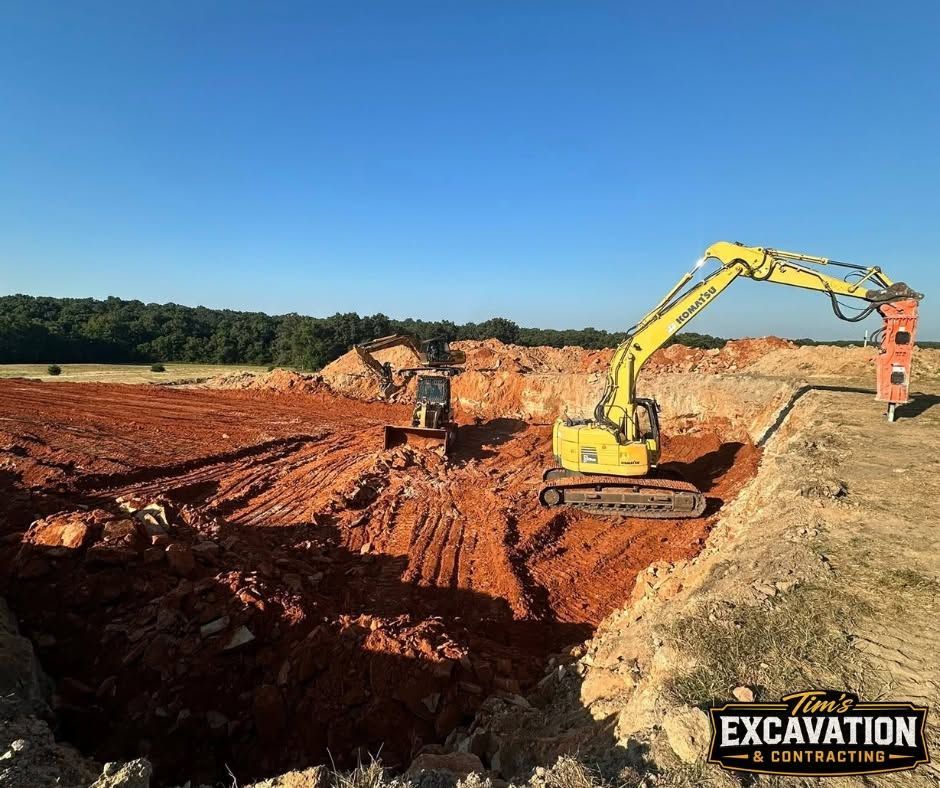 Excavator working in a red dirt construction pit under a clear blue sky