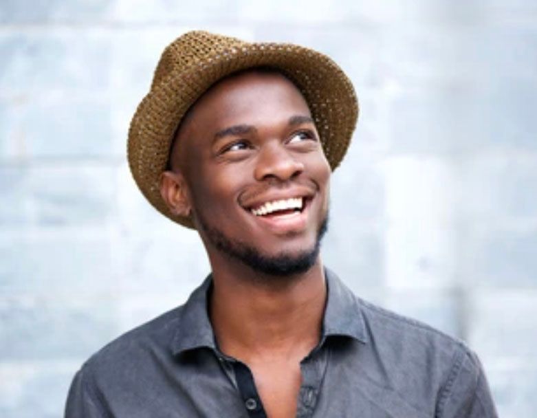 A man wearing a straw hat is smiling and looking up.