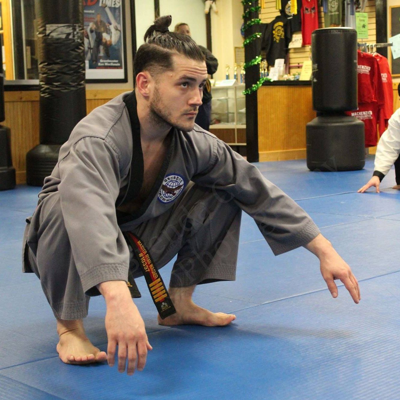 a man in a karate uniform is squatting on a blue mat