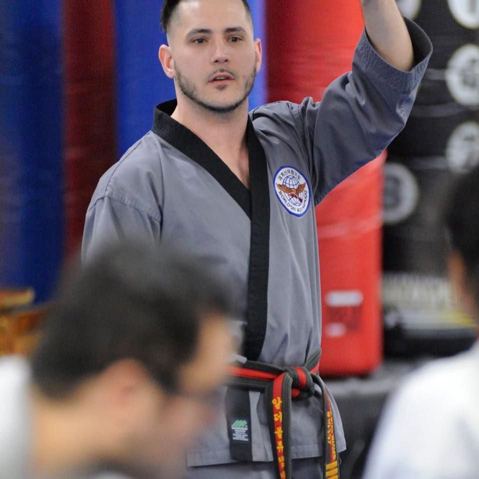 a man in a taekwondo uniform holds his hand up