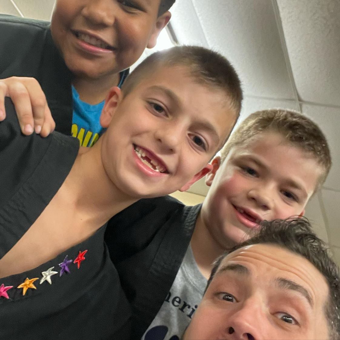 a group of young boys are posing for a picture with a man wearing a gray shirt that says leri