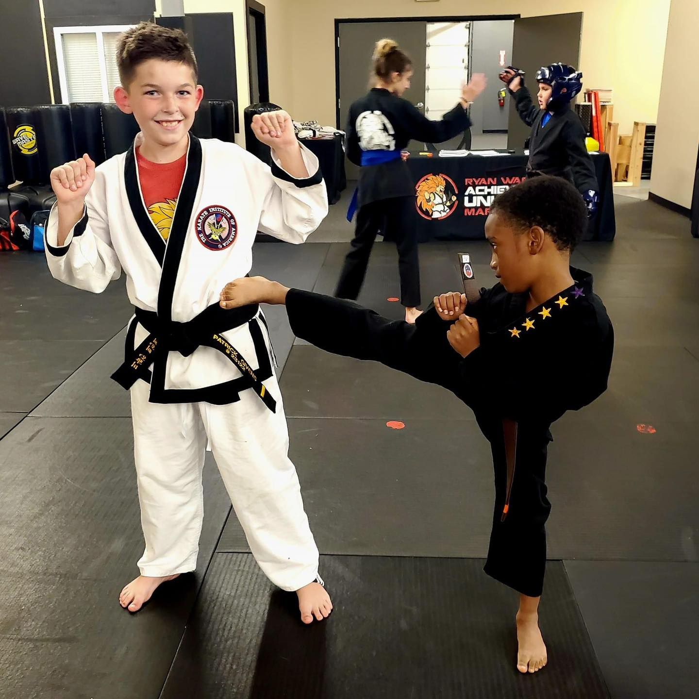 a boy and a girl are practicing martial arts in front of a table that says martial arts academy