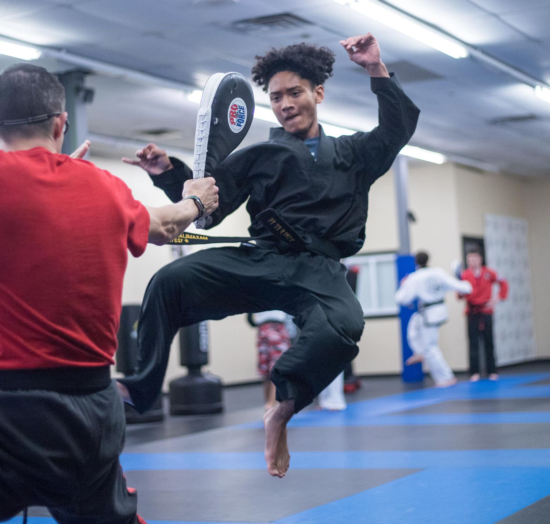 a man in a black karate uniform is jumping in the air