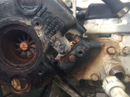 Close-up view of a dirty, grease-covered automotive turbocharger engine component.