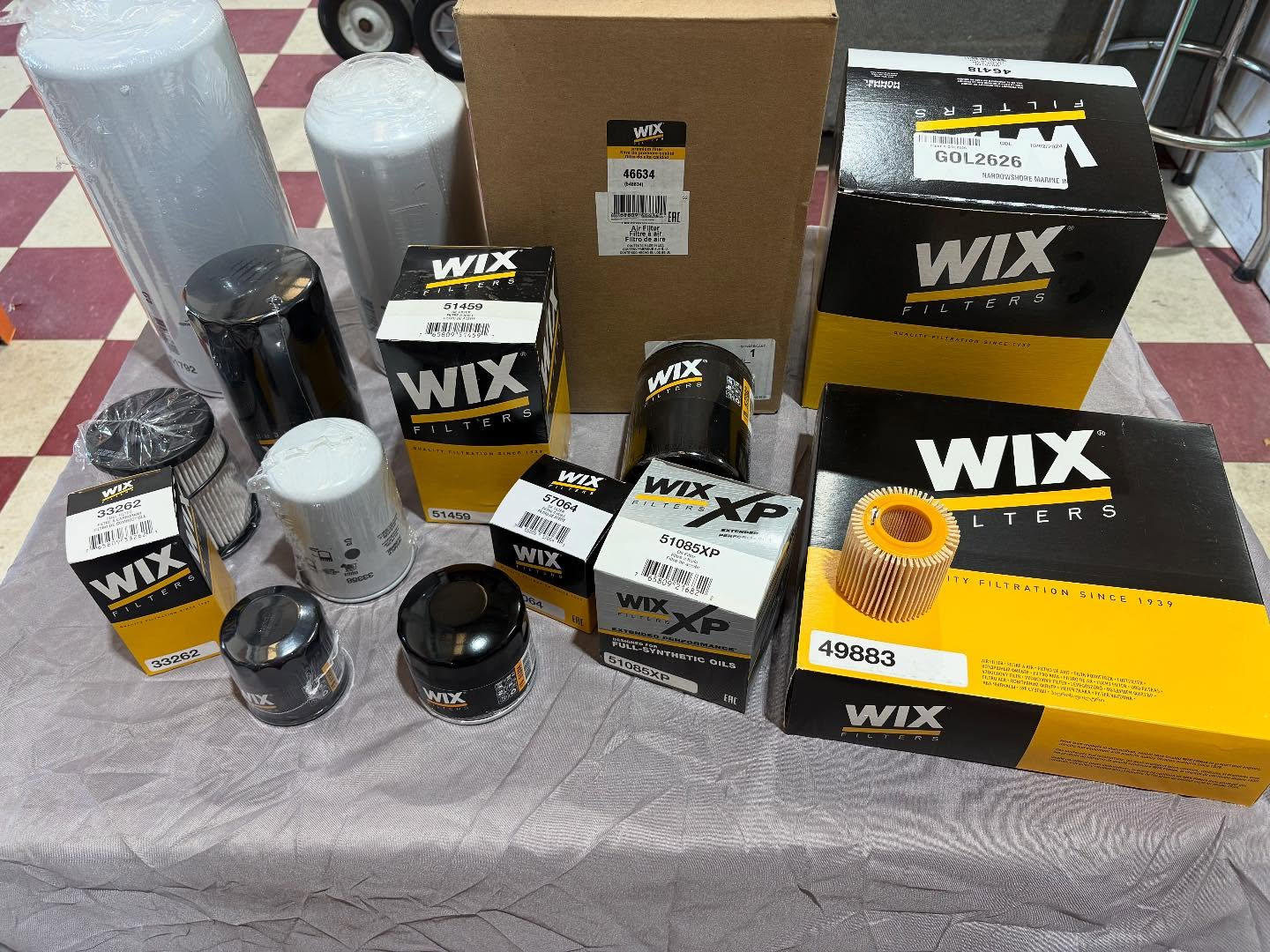 An assortment of WIX-branded automotive oil filters and boxes arranged on a white cloth surface.