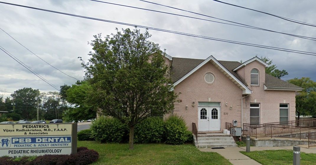 A pink house with a sign in front of it that says ped dental