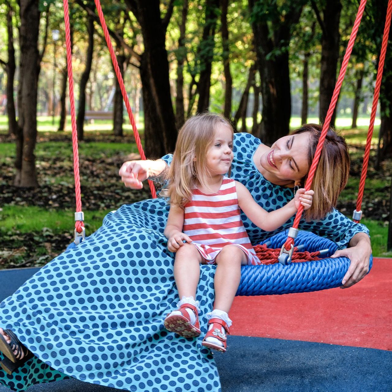 A woman is sitting on a swing with a little girl