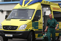 A man is standing in front of an ambulance that says emergency