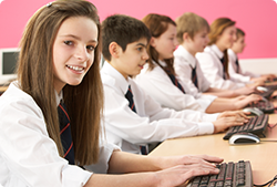 A group of children are sitting at desks in front of computers.