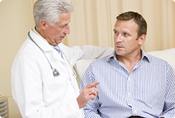 A doctor is talking to a patient who is sitting on a couch.