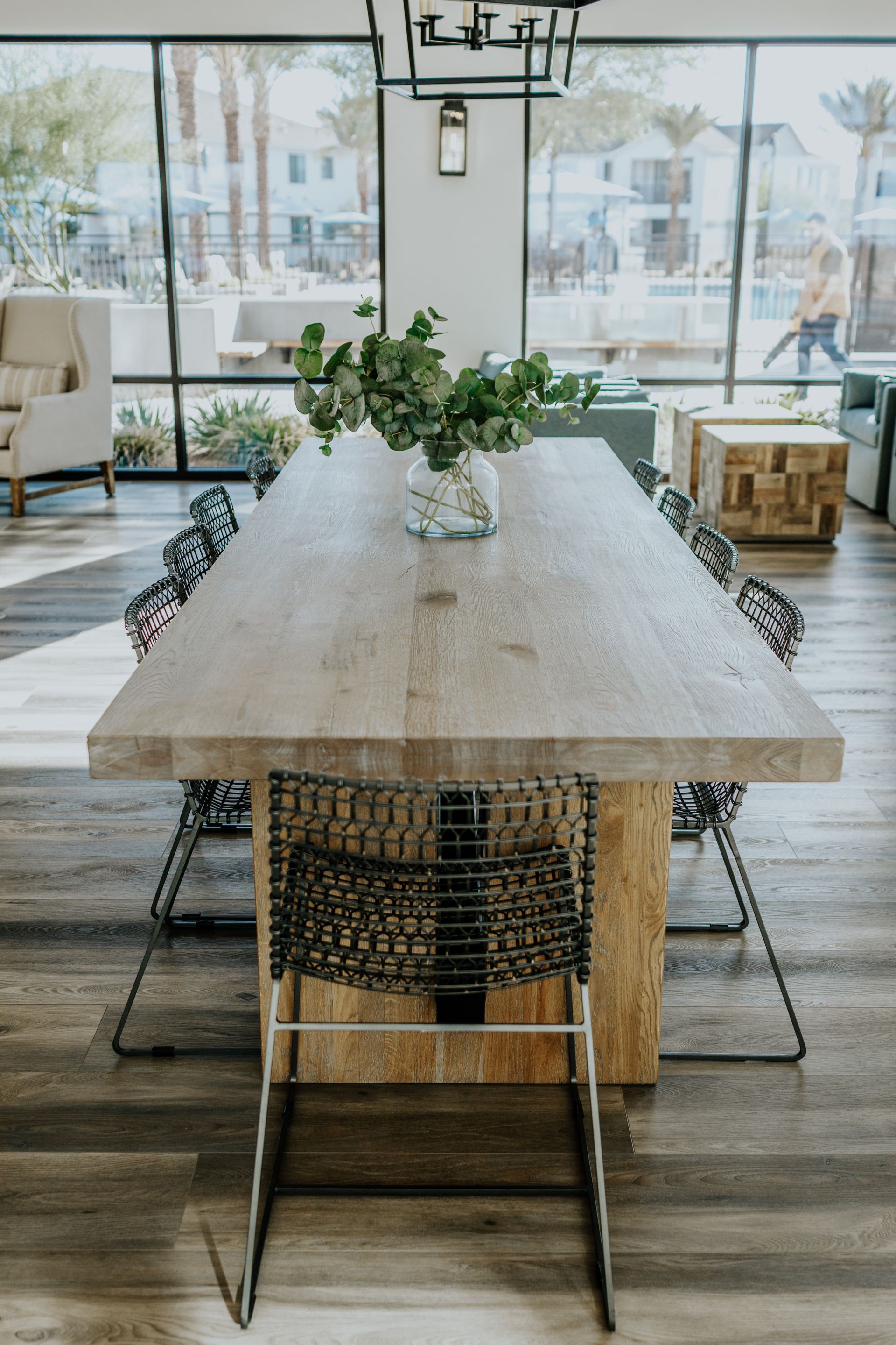 A long wooden table with a vase of flowers on it in a living room.