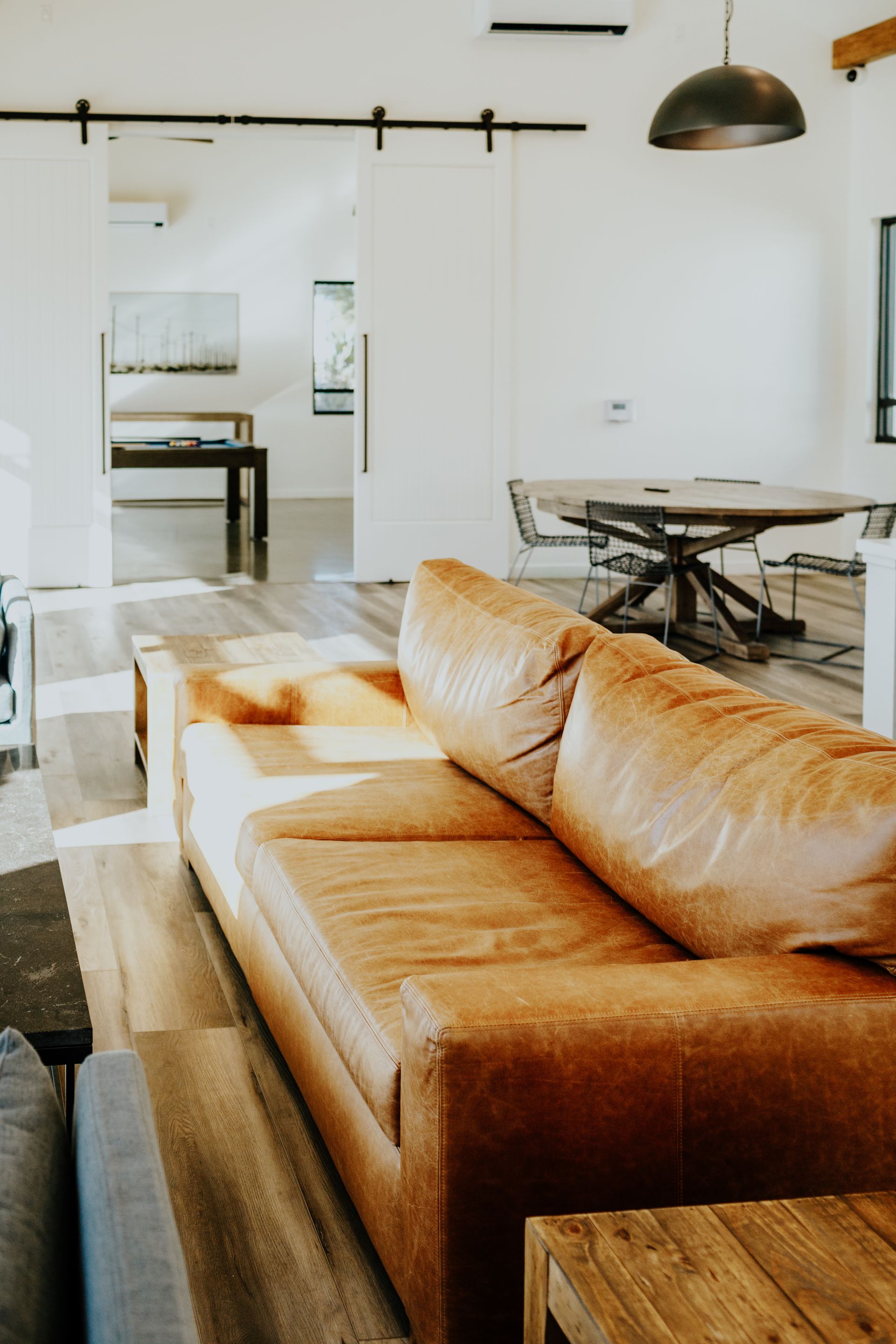 A living room with a brown leather couch and a wooden table.