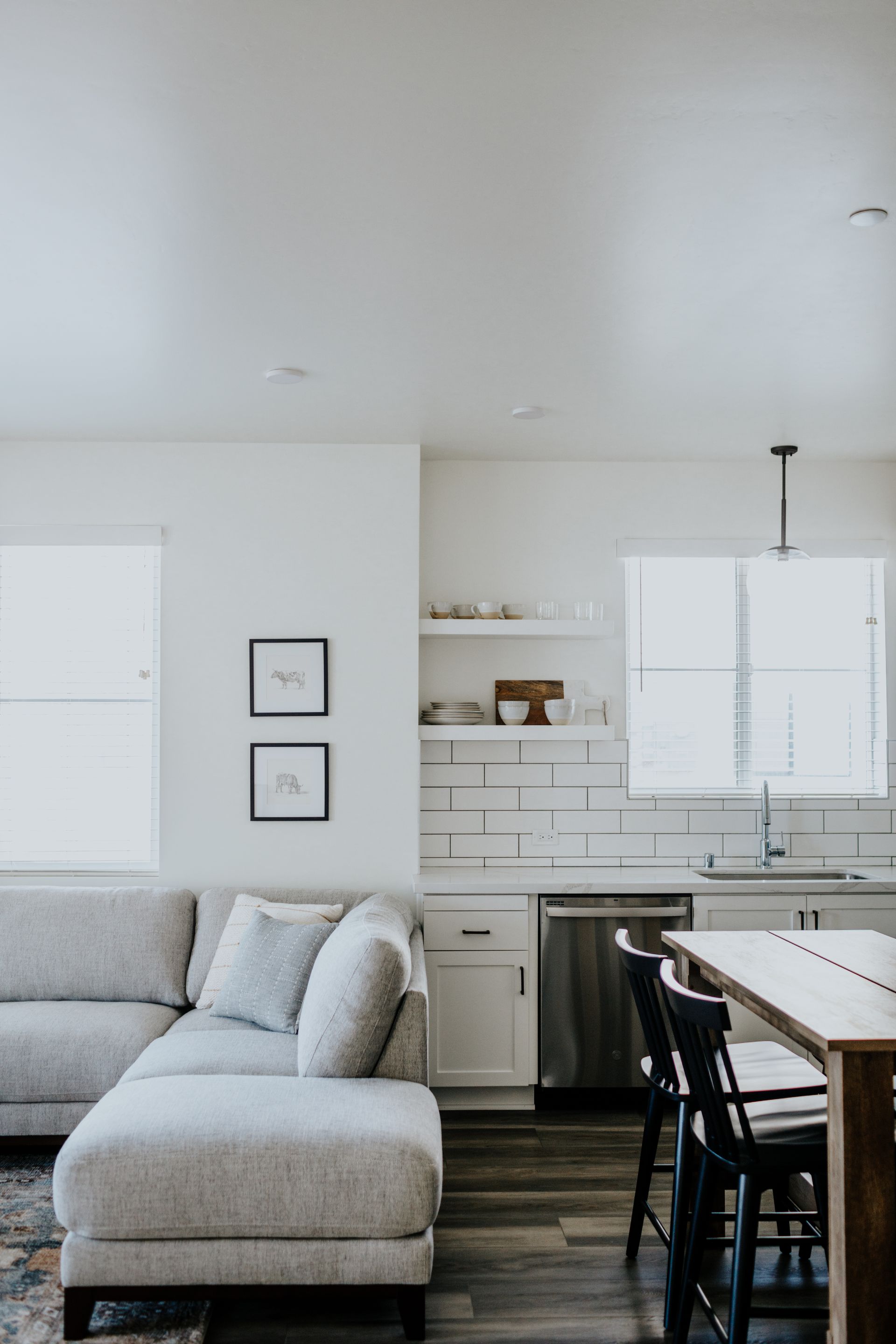 A living room with a sectional couch and a kitchen.