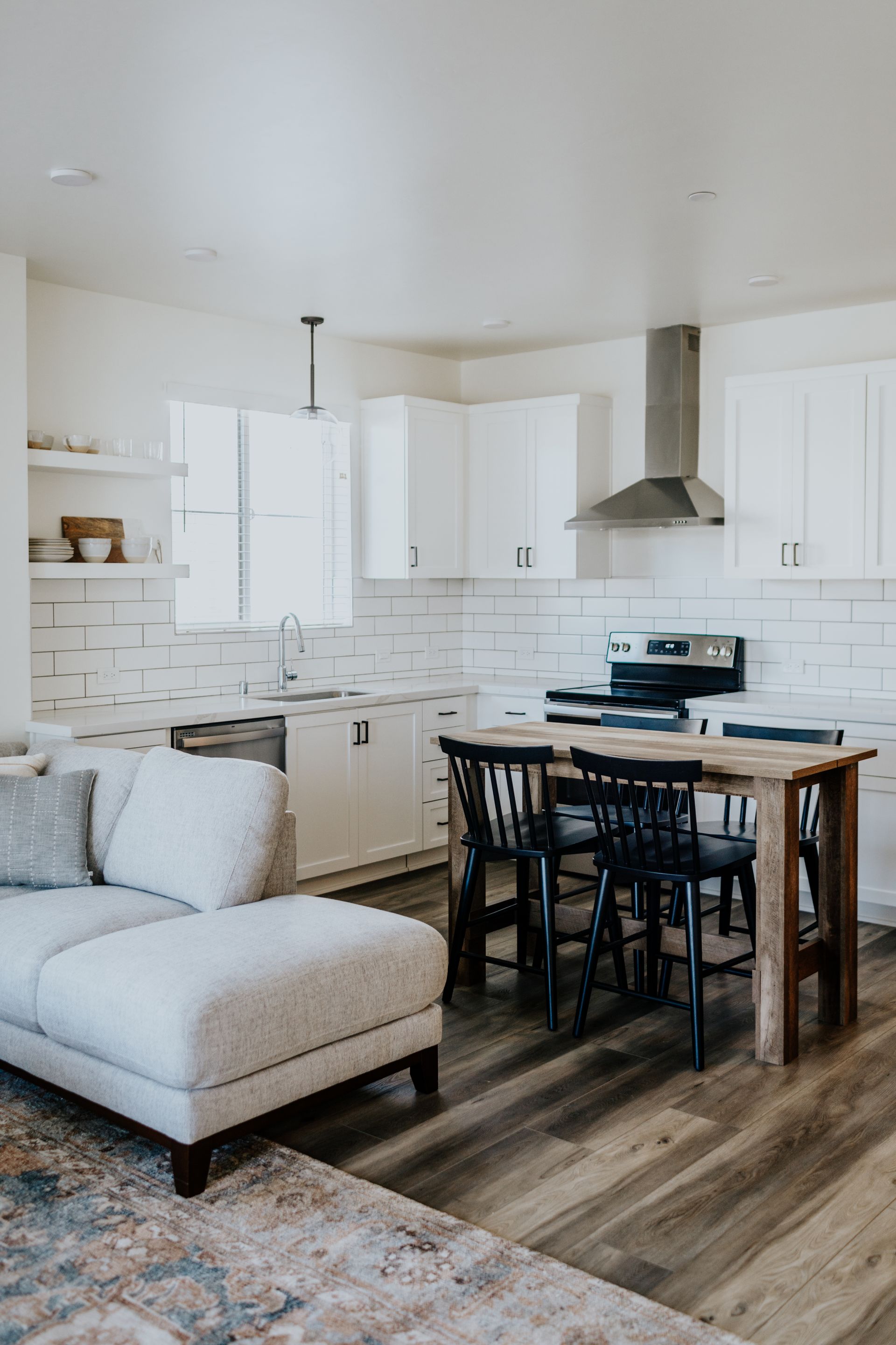 A living room with a couch , table , chairs and a kitchen.