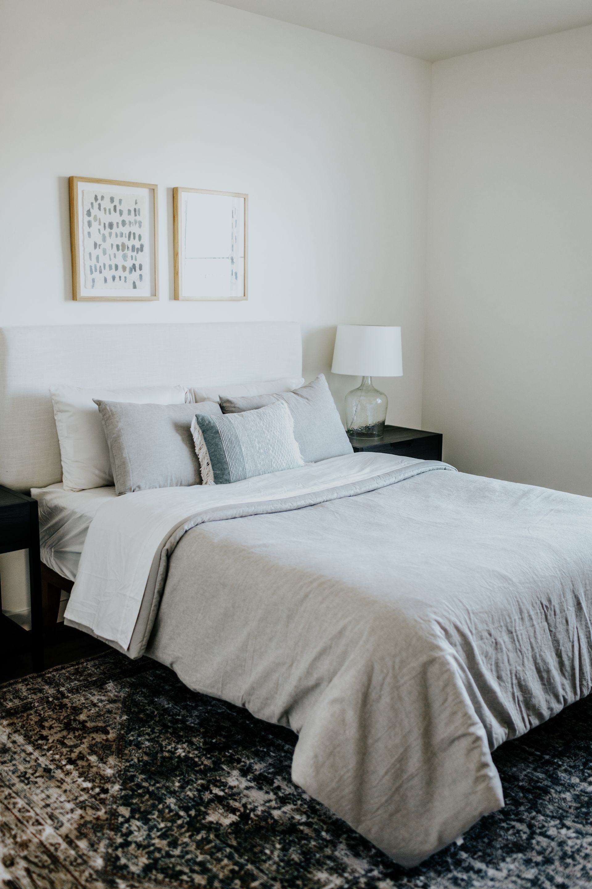 A bedroom with a bed , nightstand , lamp and rug.