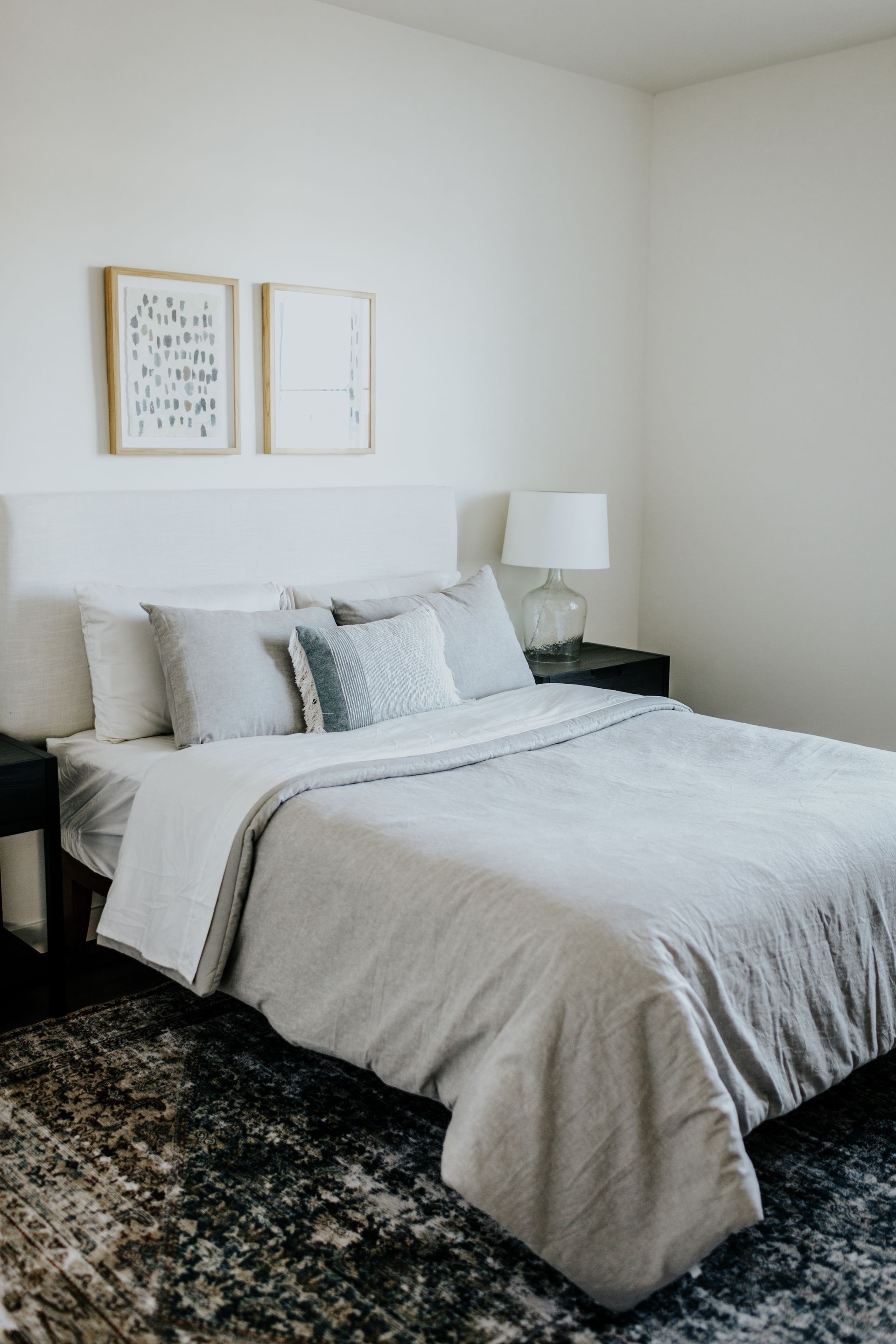 Bed featuring light gray bedding and multiple throw pillows. 