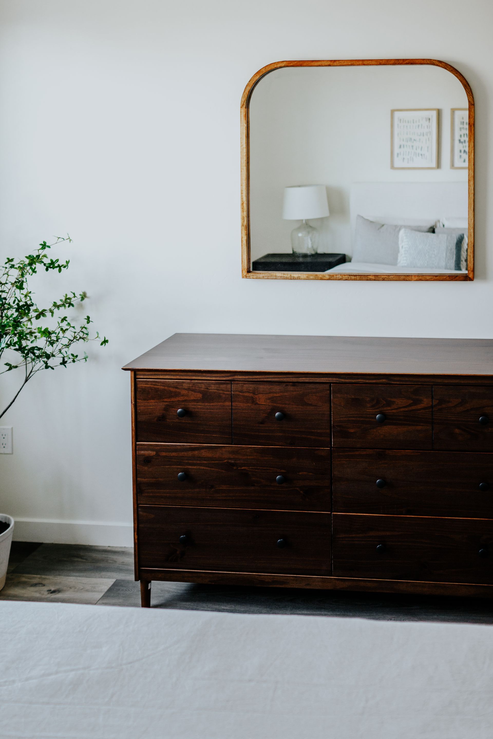 A bedroom with a dresser and a mirror on the wall.