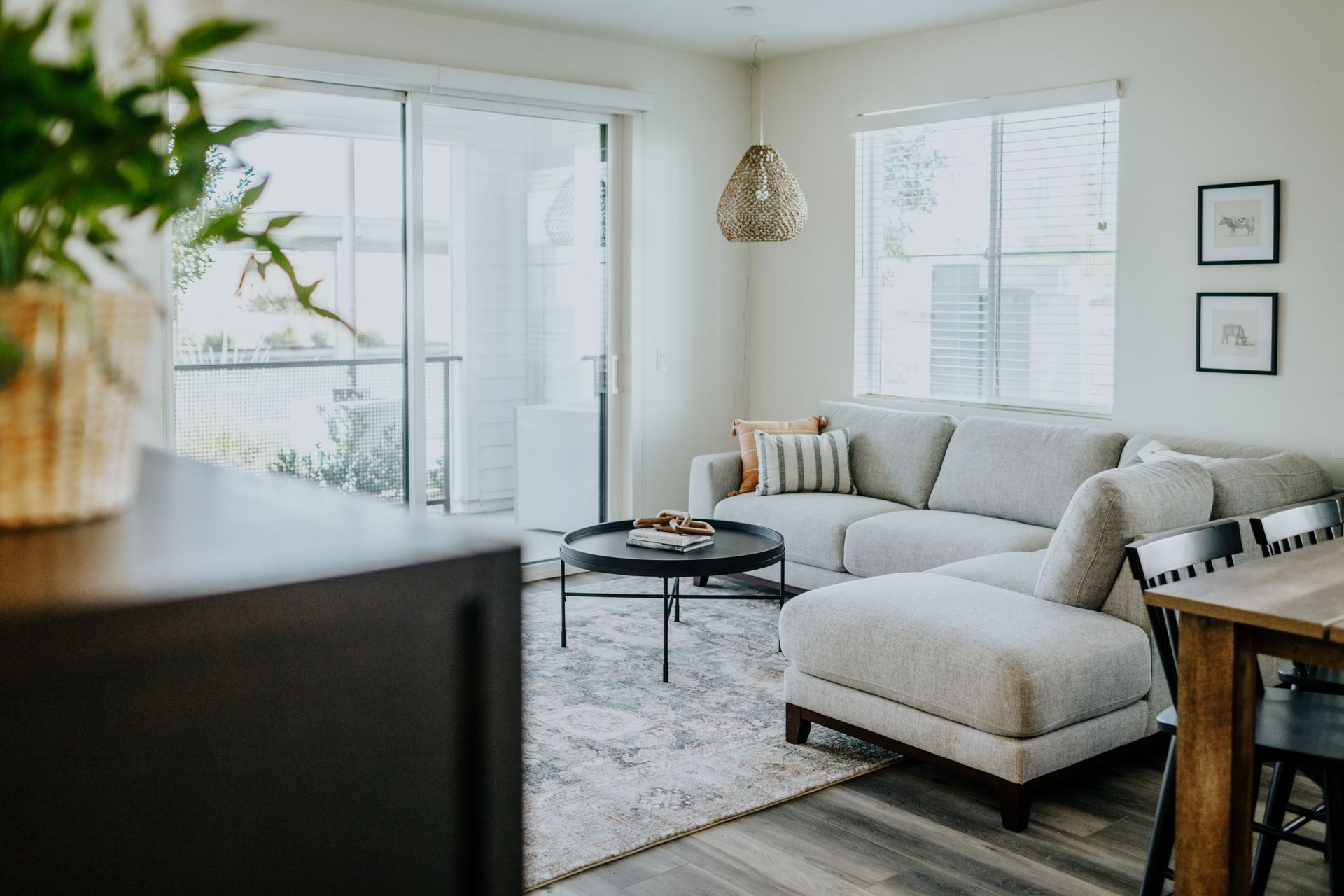 Modern living room with a light gray sectional sofa, patterned rug, and round black coffee table.