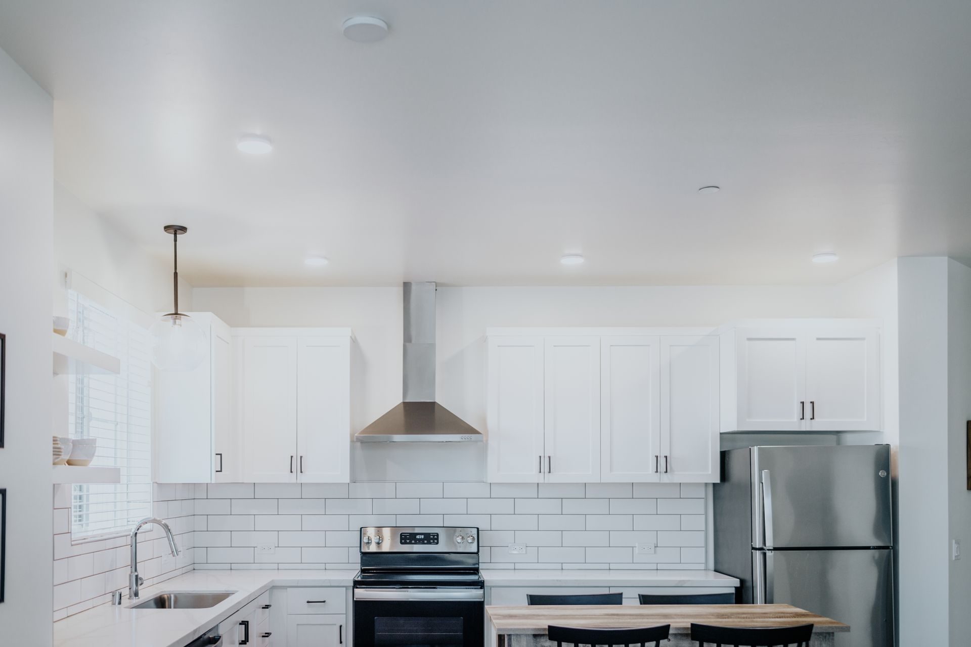 A kitchen with white cabinets , stainless steel appliances , a refrigerator and a sink.