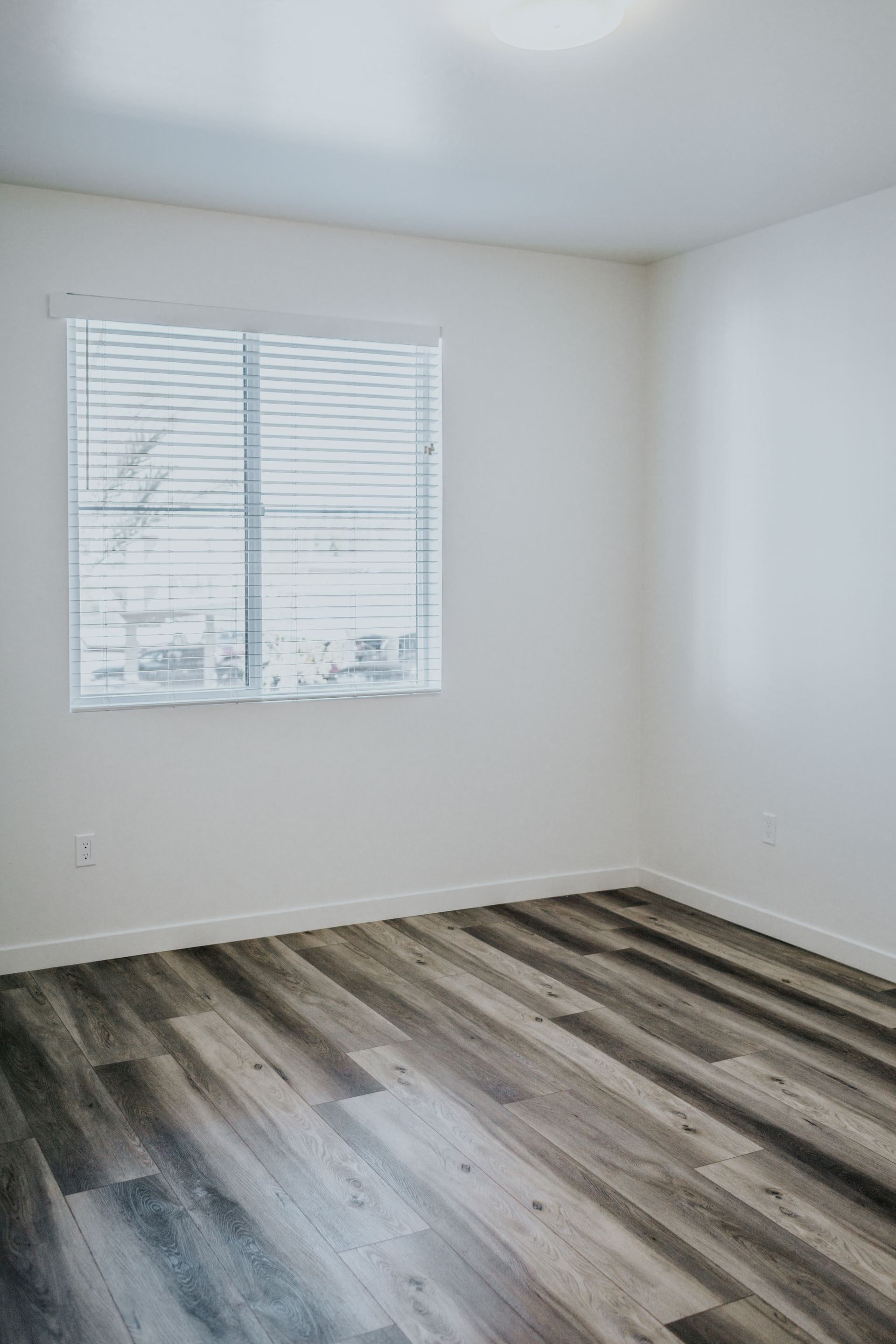 An empty bedroom with hardwood floors and a window.