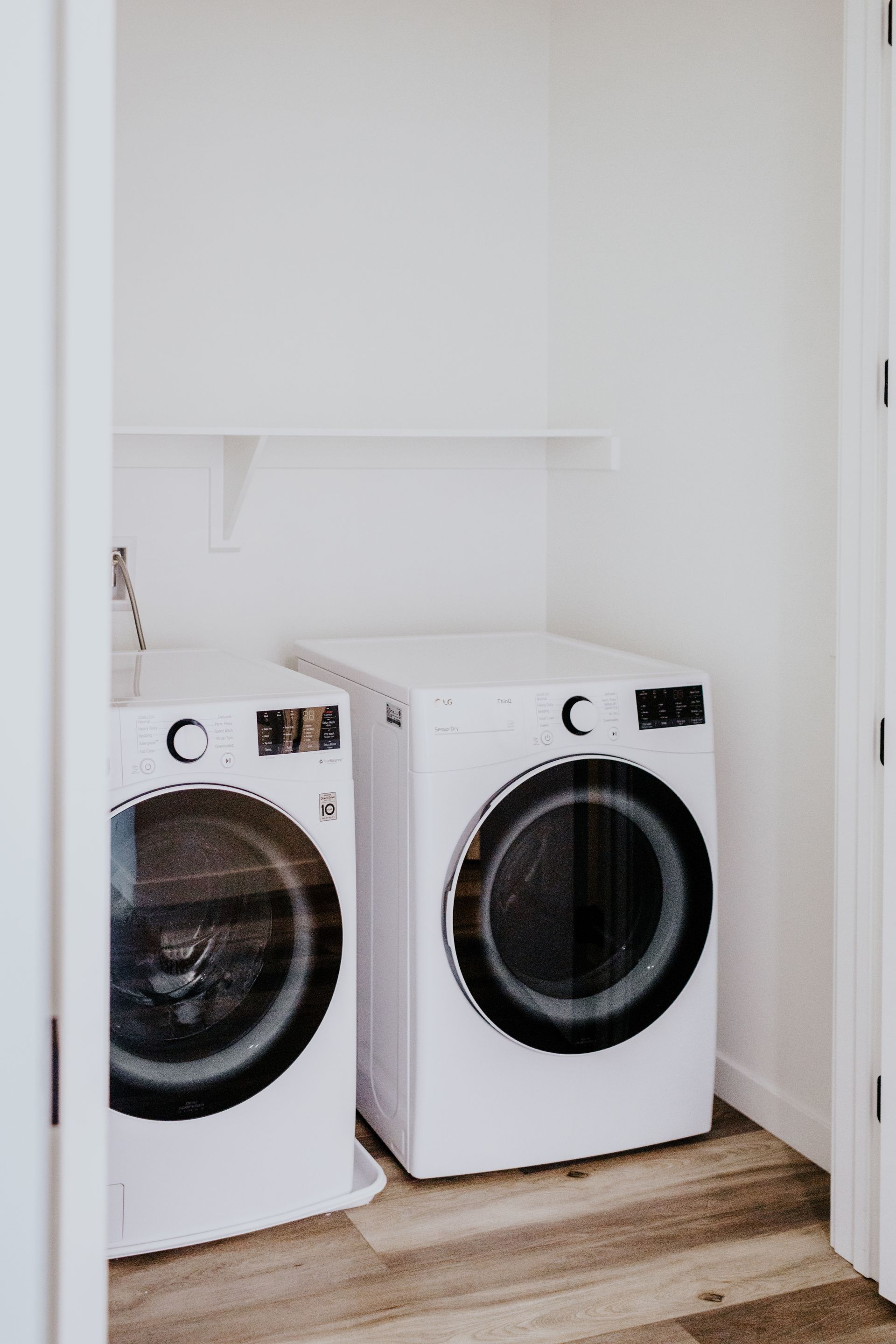 Two white washers and dryers are sitting next to each other in a laundry room.