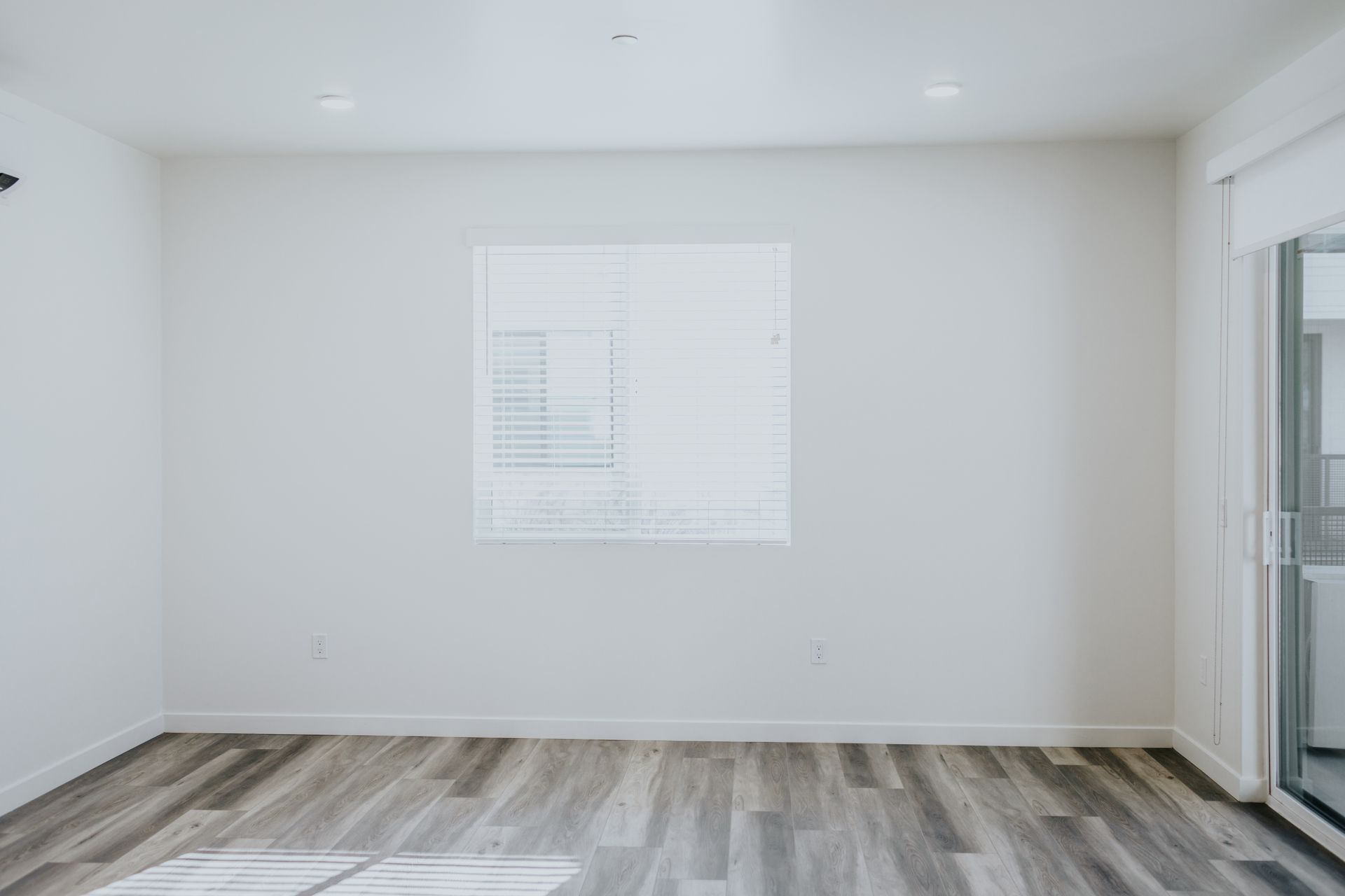 An empty room with hardwood floors and a window.