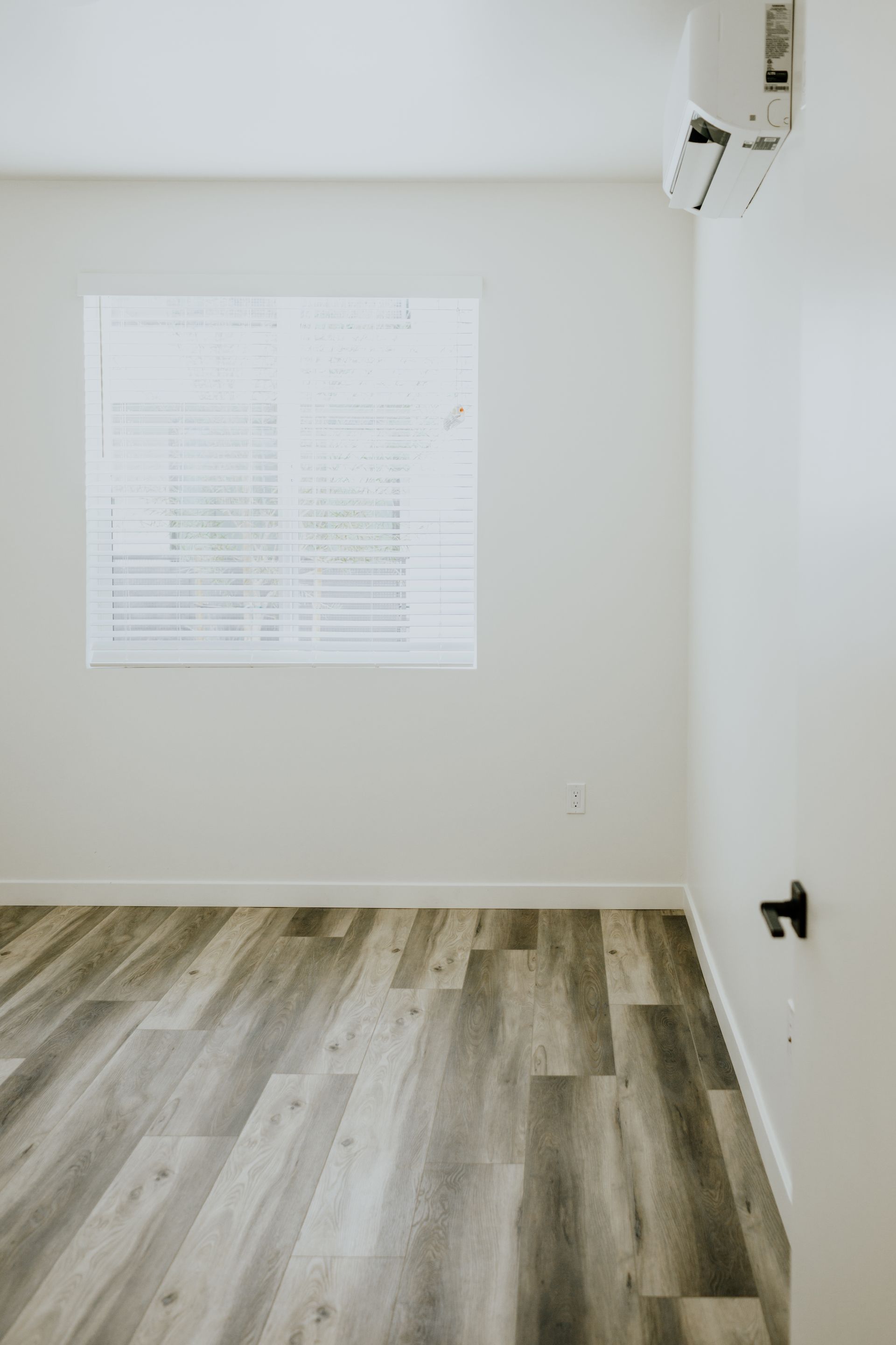 An empty room with hardwood floors and a window.