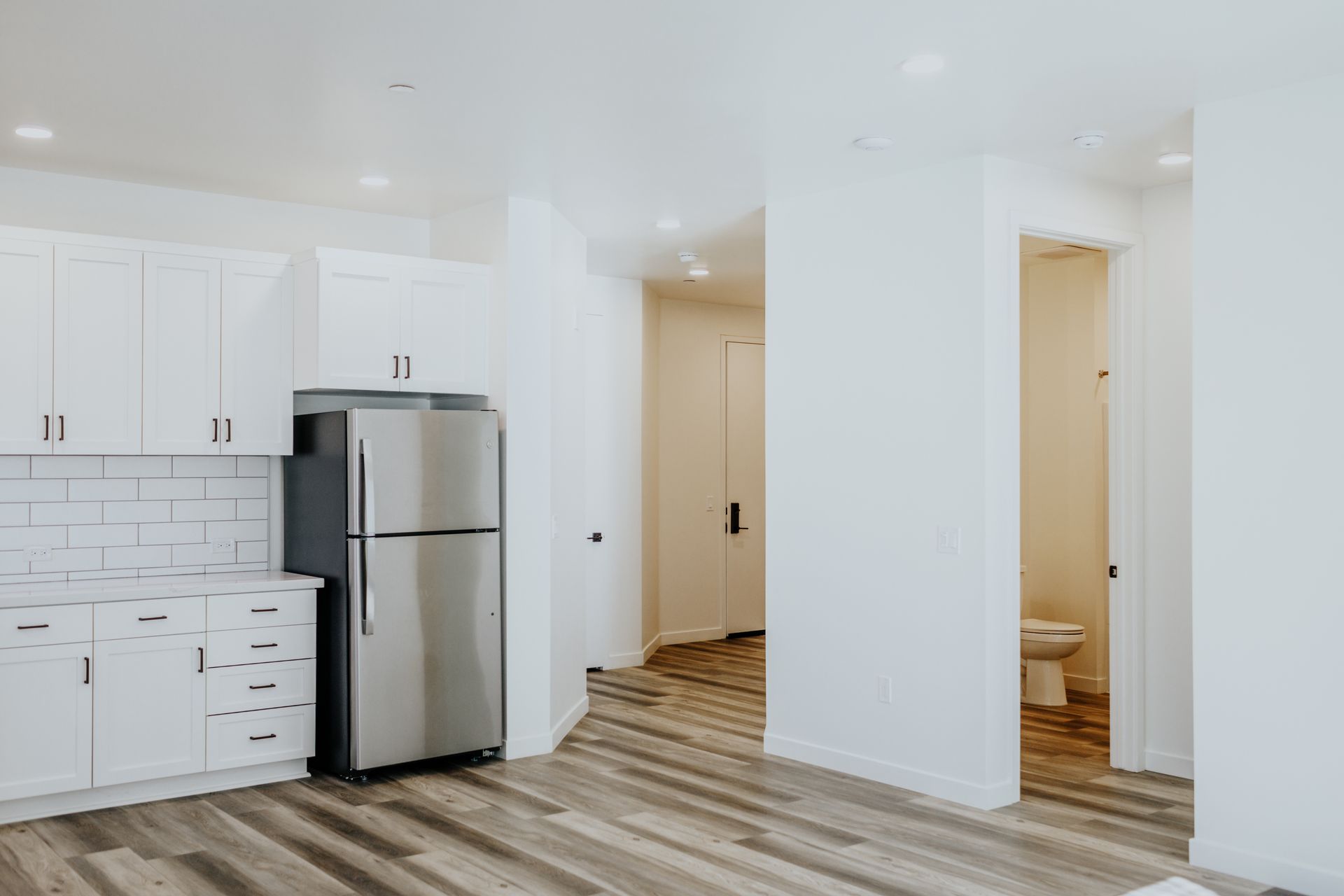 A kitchen with a stainless steel refrigerator and white cabinets.