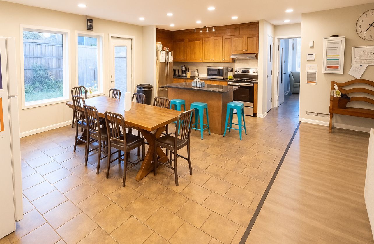 Spacious kitchen with a large wooden table, a kitchen island with stools, and windows.