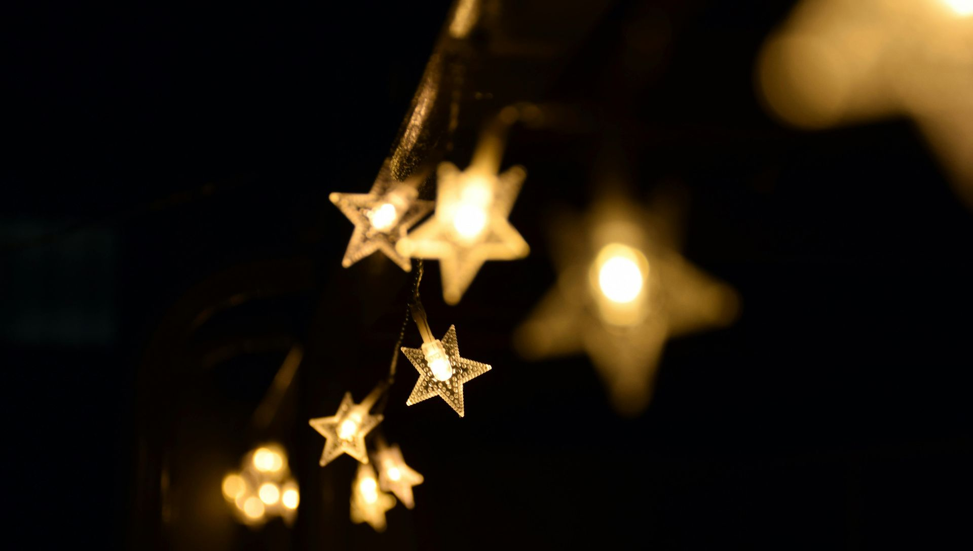 String of illuminated star-shaped lights against a dark background, creating a warm, festive glow.