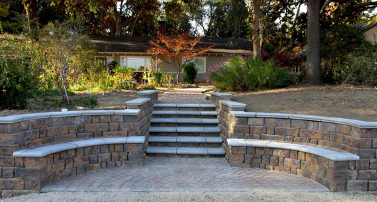 A stone wall with stairs leading up to a house